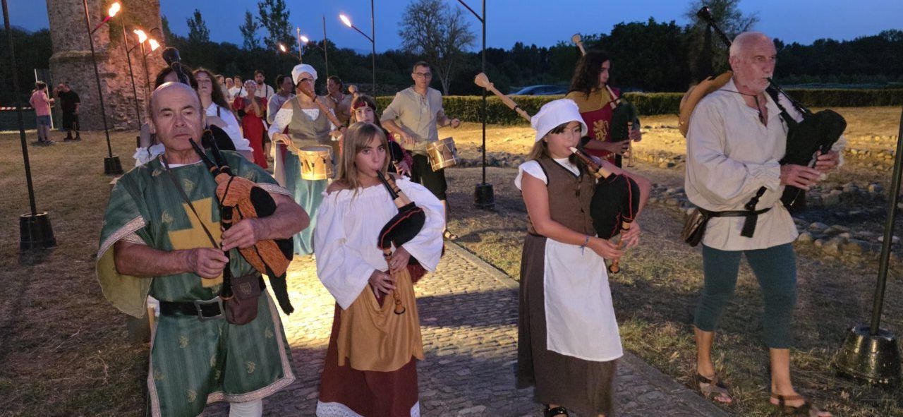 Grupo de personas en vestimenta medieval tocando instrumentos durante un recorrido teatralizado