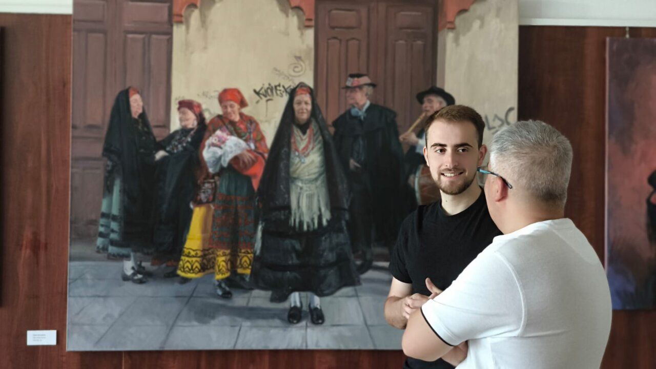 Artistas conversando frente a una pintura en la exposición de Guillermo Otero