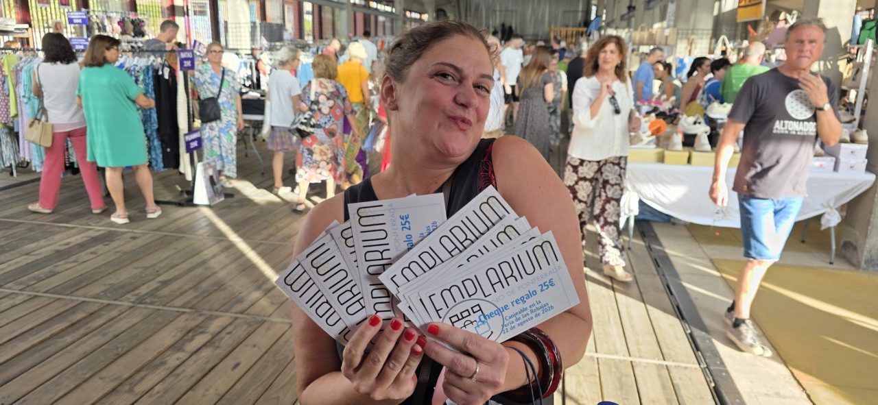 Mujer sonriente sosteniendo cheques regalo en la Feria de las Rebajas