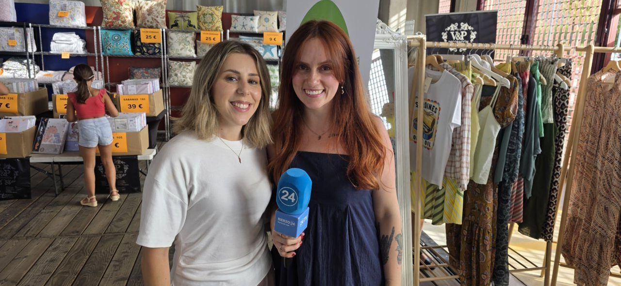 Dos mujeres sonrientes en la Feria de las Rebajas con productos de fondo