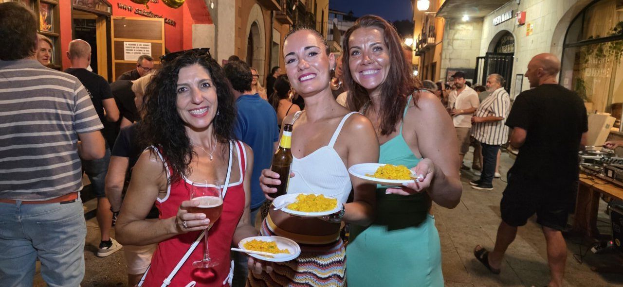 Tres mujeres sonrientes sosteniendo platos de comida en una celebración