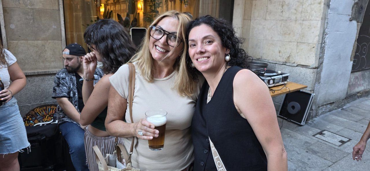 Dos mujeres sonrientes sosteniendo una cerveza en la celebración del aniversario