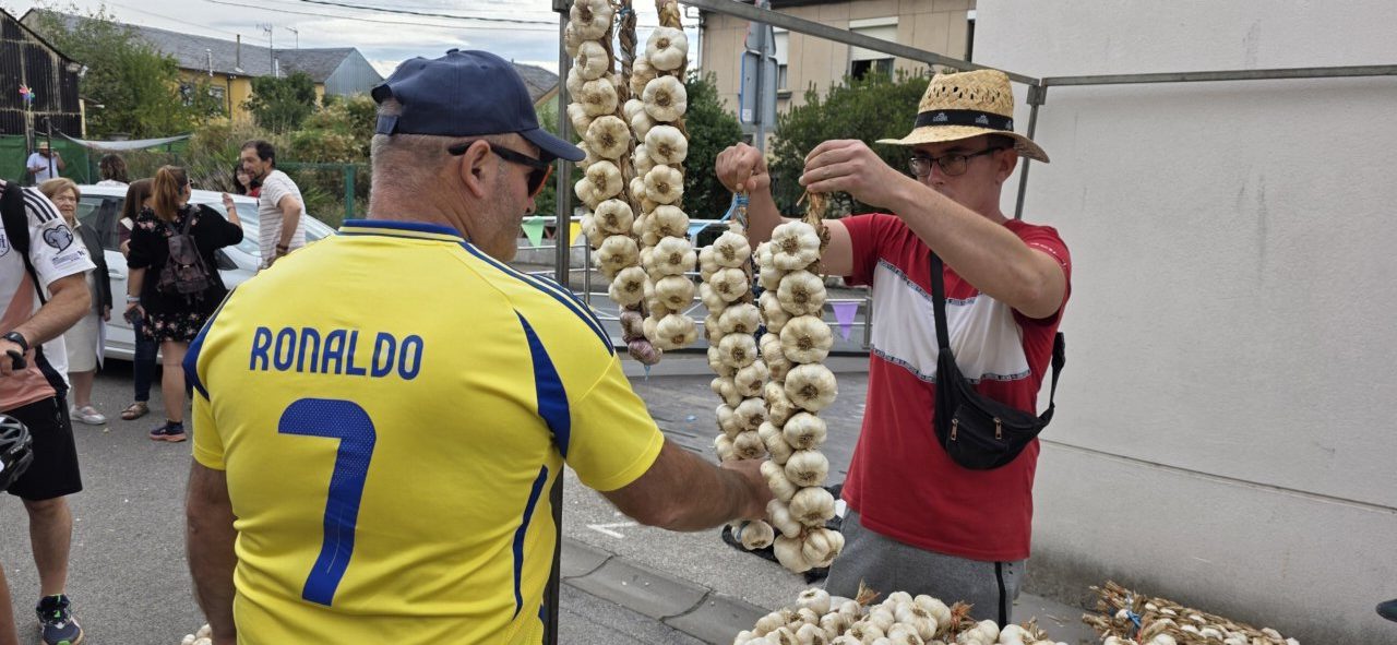 Personas en la Feria del Ajo de San Miguel de las Dueñas mostrando ajos