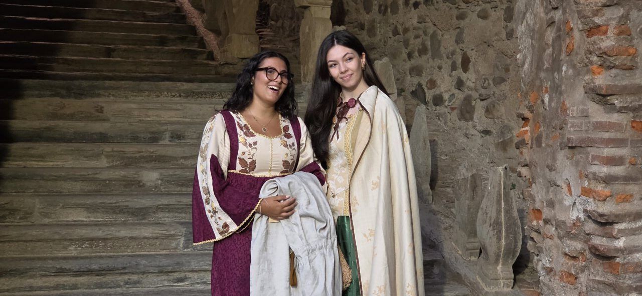Dos mujeres vestidas con trajes medievales en un entorno histórico