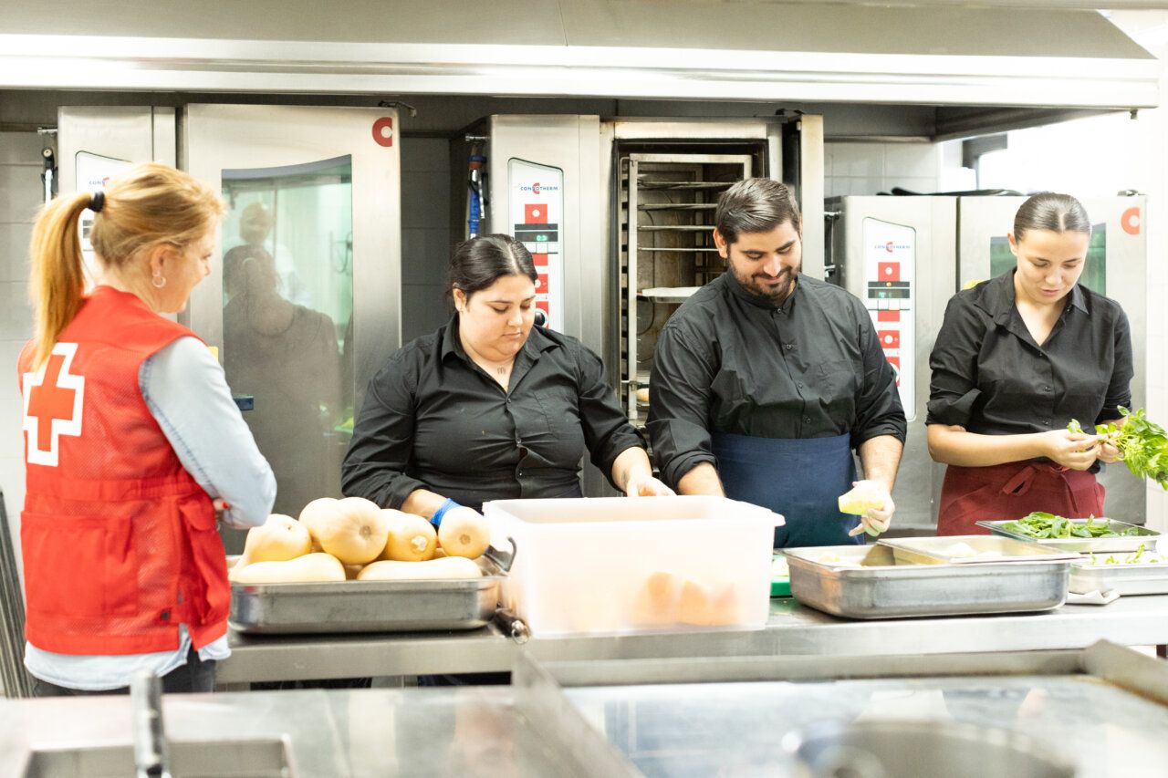 Grupo de personas trabajando en una cocina con apoyo de Cruz Roja