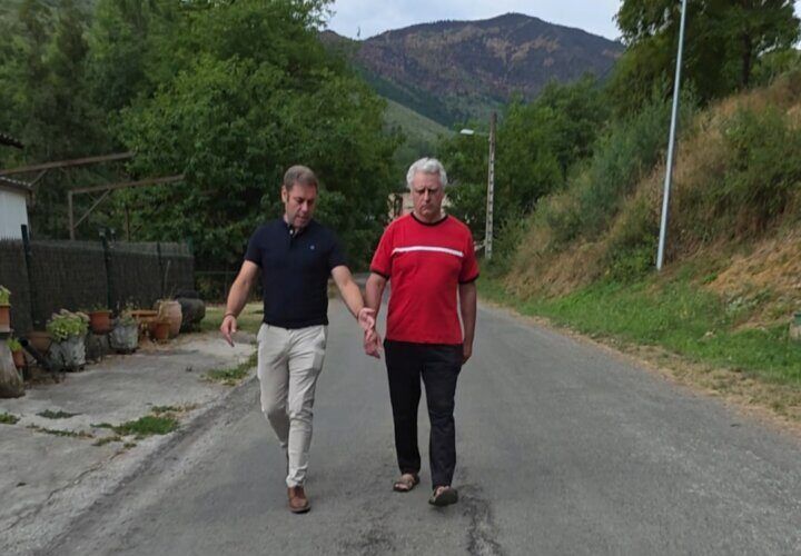 Dos hombres caminando por una carretera en mal estado