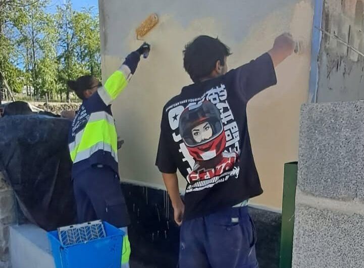 Dos trabajadores aplicando pintura en una pared durante un proyecto de albañilería
