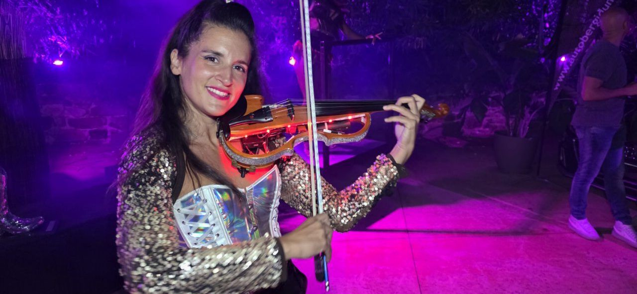 Mujer tocando un violín iluminado en un evento festivo