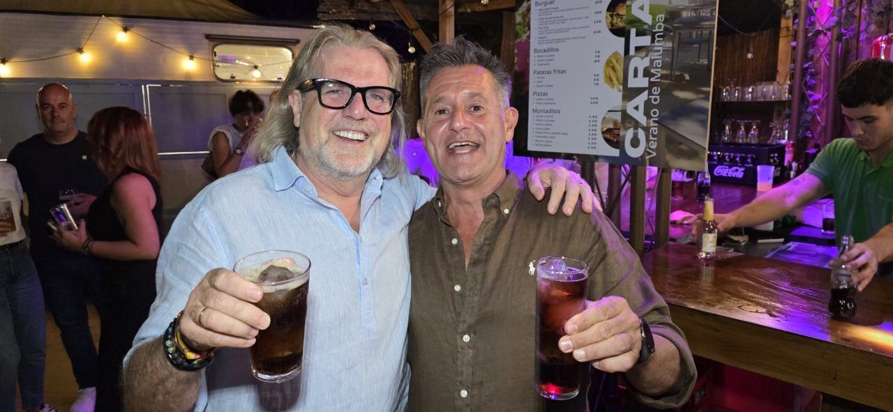 Dos hombres celebrando con bebidas en la Terraza Malumba durante el homenaje a Ángela Show