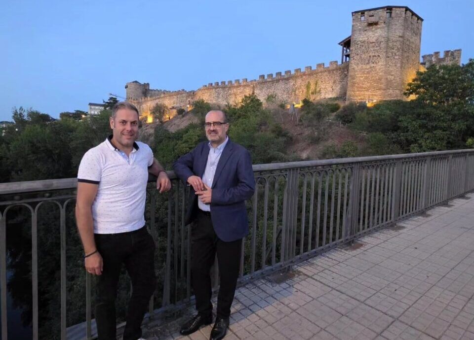 Dos hombres posando frente al Castillo de los Templarios iluminado