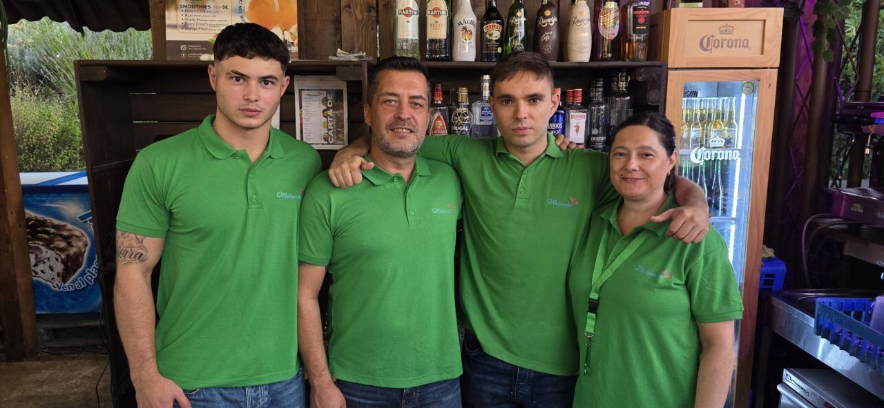 Cuatro personas en camisetas verdes en un bar de Malumba