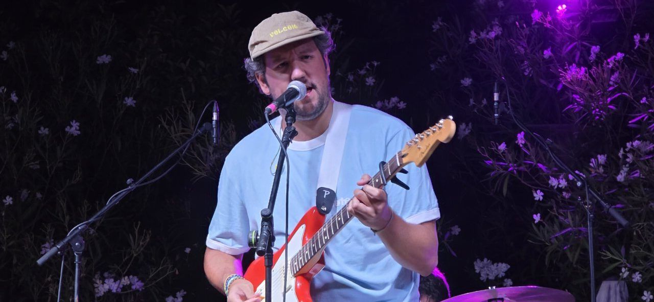 Artista Pavlenha tocando la guitarra en un concierto en Malumba