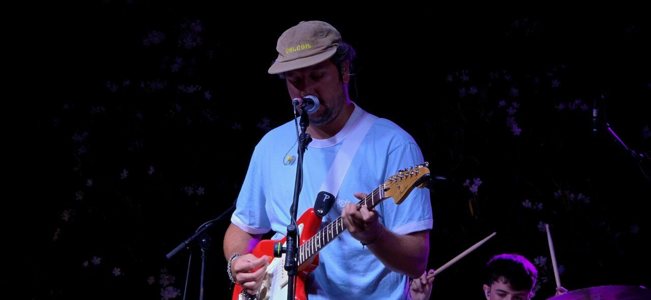 Artista Pavlenha tocando la guitarra en un concierto en Malumba