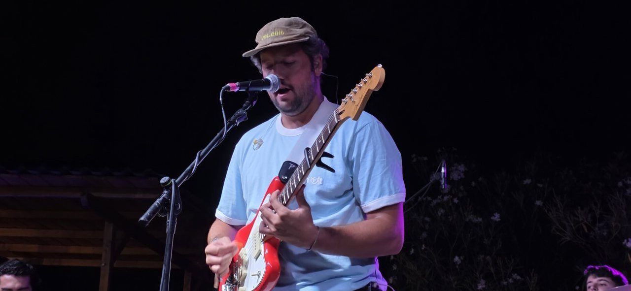 Artista Pavlenha tocando la guitarra en un concierto en Malumba