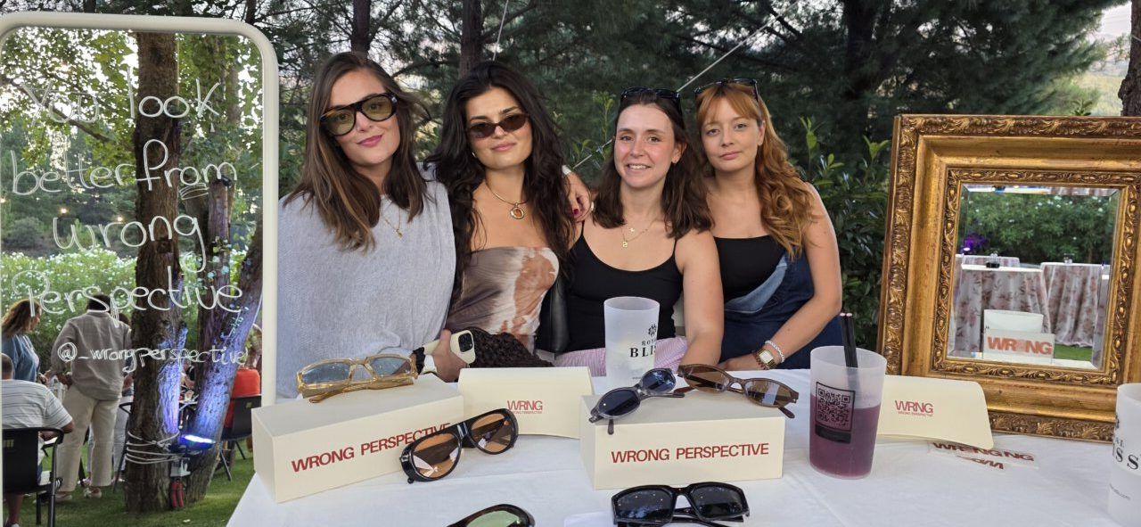 Cuatro mujeres posando con gafas de sol en un evento local