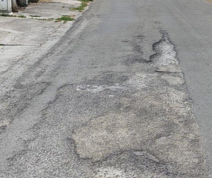 Carretera en mal estado con baches y grietas visibles