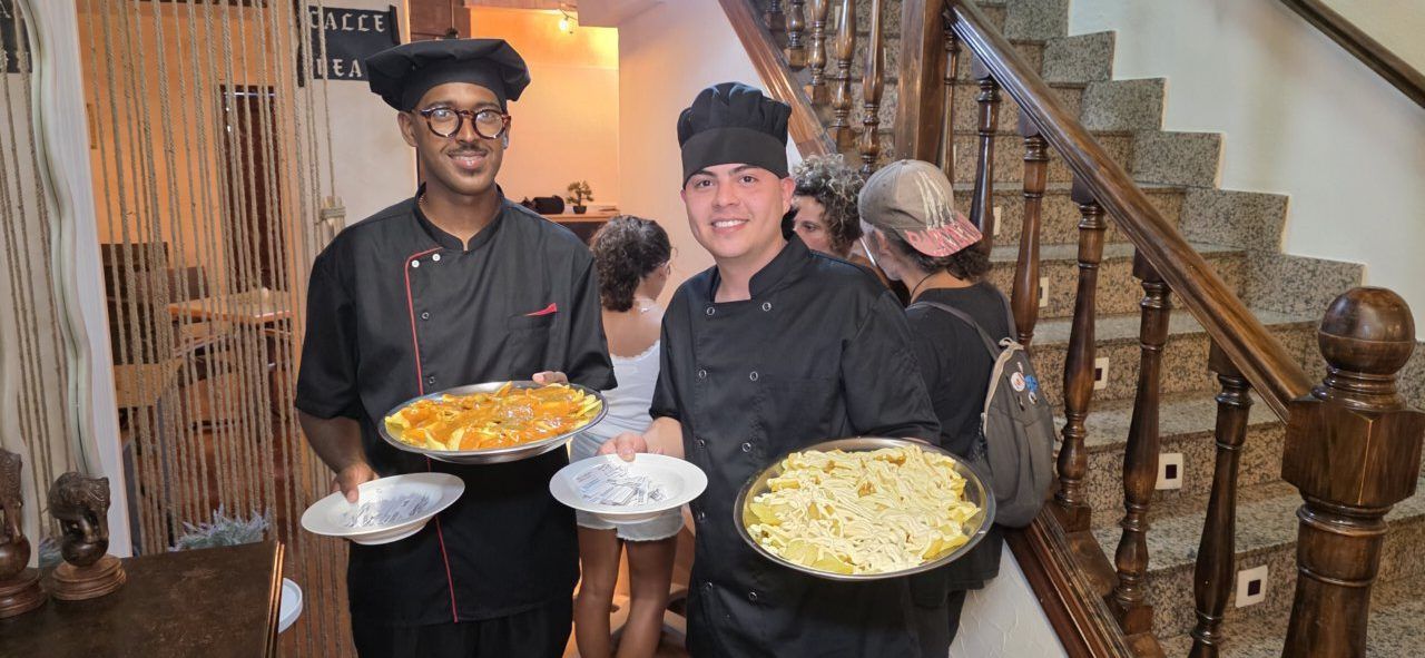 Dos chefs sosteniendo platos de comida en un evento de música y comercio local.