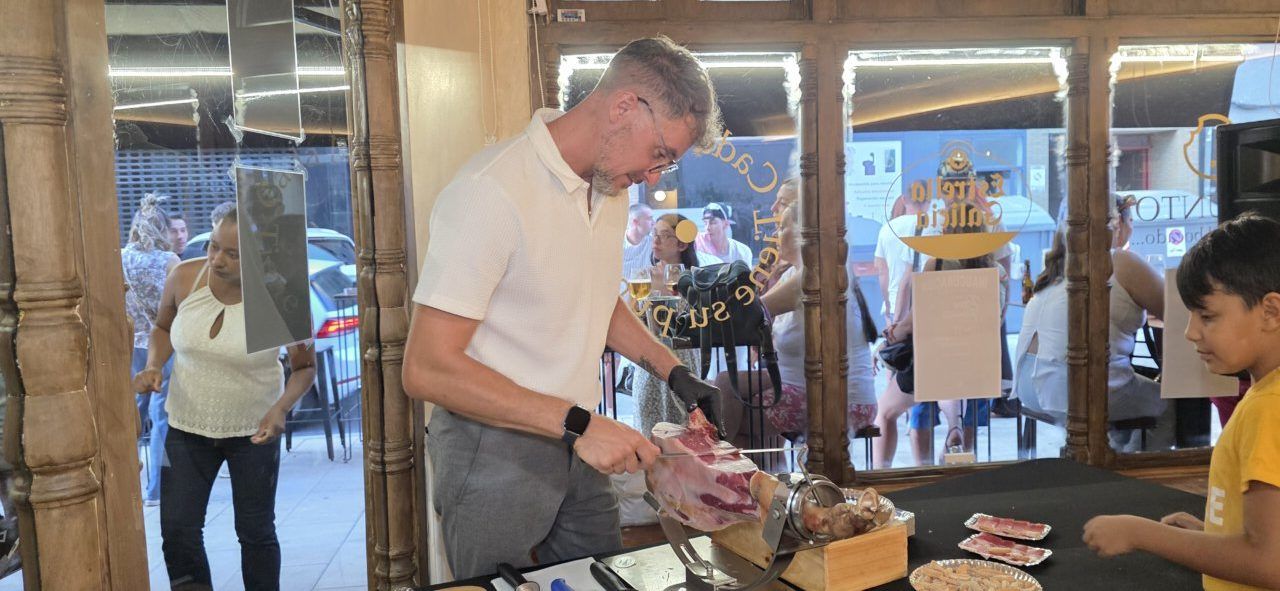Un hombre cortando jamón en un evento musical en Ponferrada.