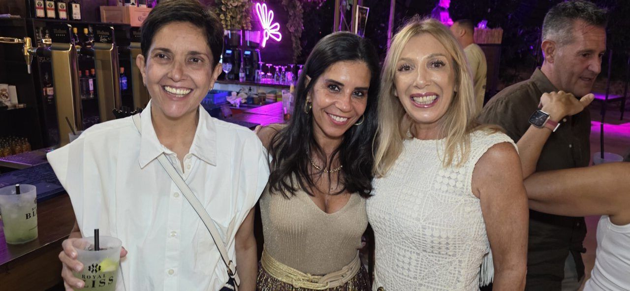 Tres mujeres sonrientes en la Terraza Malumba durante un homenaje
