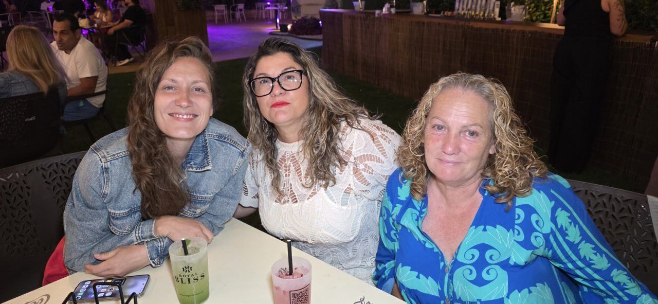 Tres mujeres sonrientes en la Terraza Malumba durante un homenaje