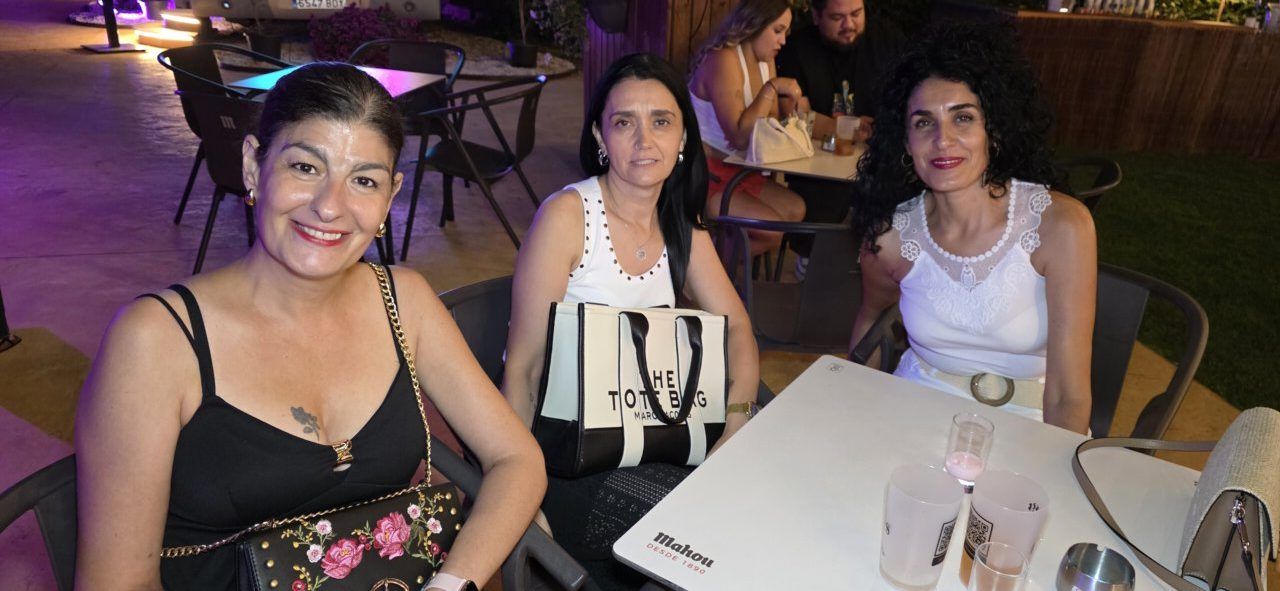 Tres mujeres sonrientes en la Terraza Malumba durante un homenaje.