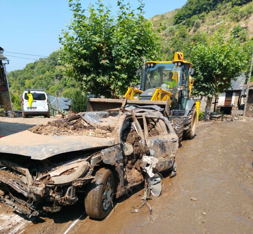Coche dañado por riadas en Manzanedo, con maquinaria de limpieza