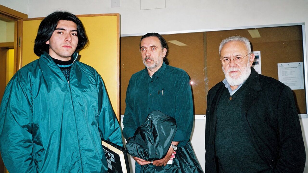 Tres hombres en un entorno de cine, uno de ellos es Gonzalo Suárez.