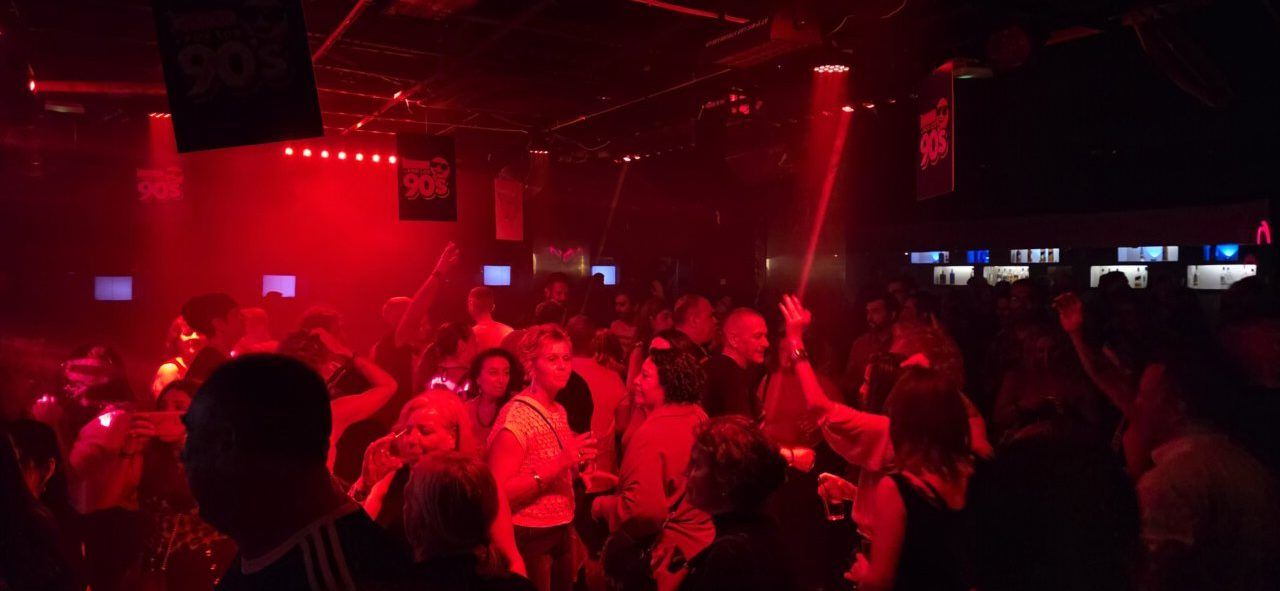 Fiesta de los 80 y 90 en la discoteca Temple de Ponferrada con luces rojas y gente bailando.