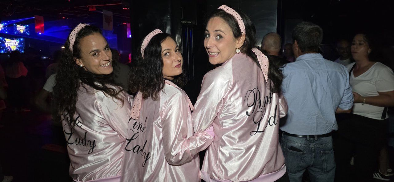 Tres mujeres con chaquetas rosas en fiesta de los 80 y 90