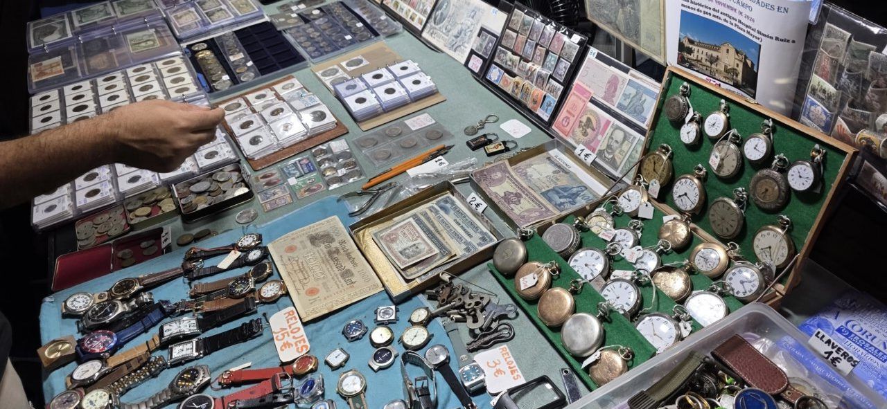 Mesa con relojes, monedas y billetes en la feria de antigüedades