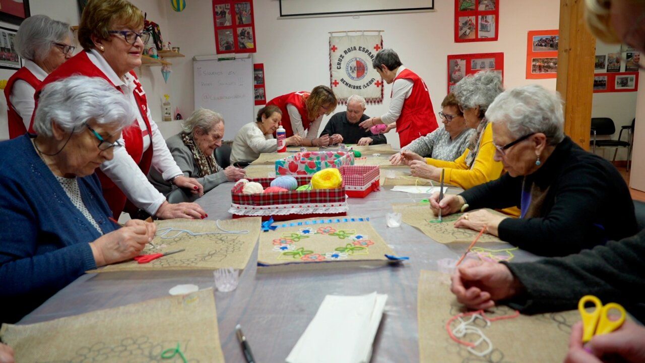 Grupo de personas mayores participando en una actividad manual con apoyo de voluntarios