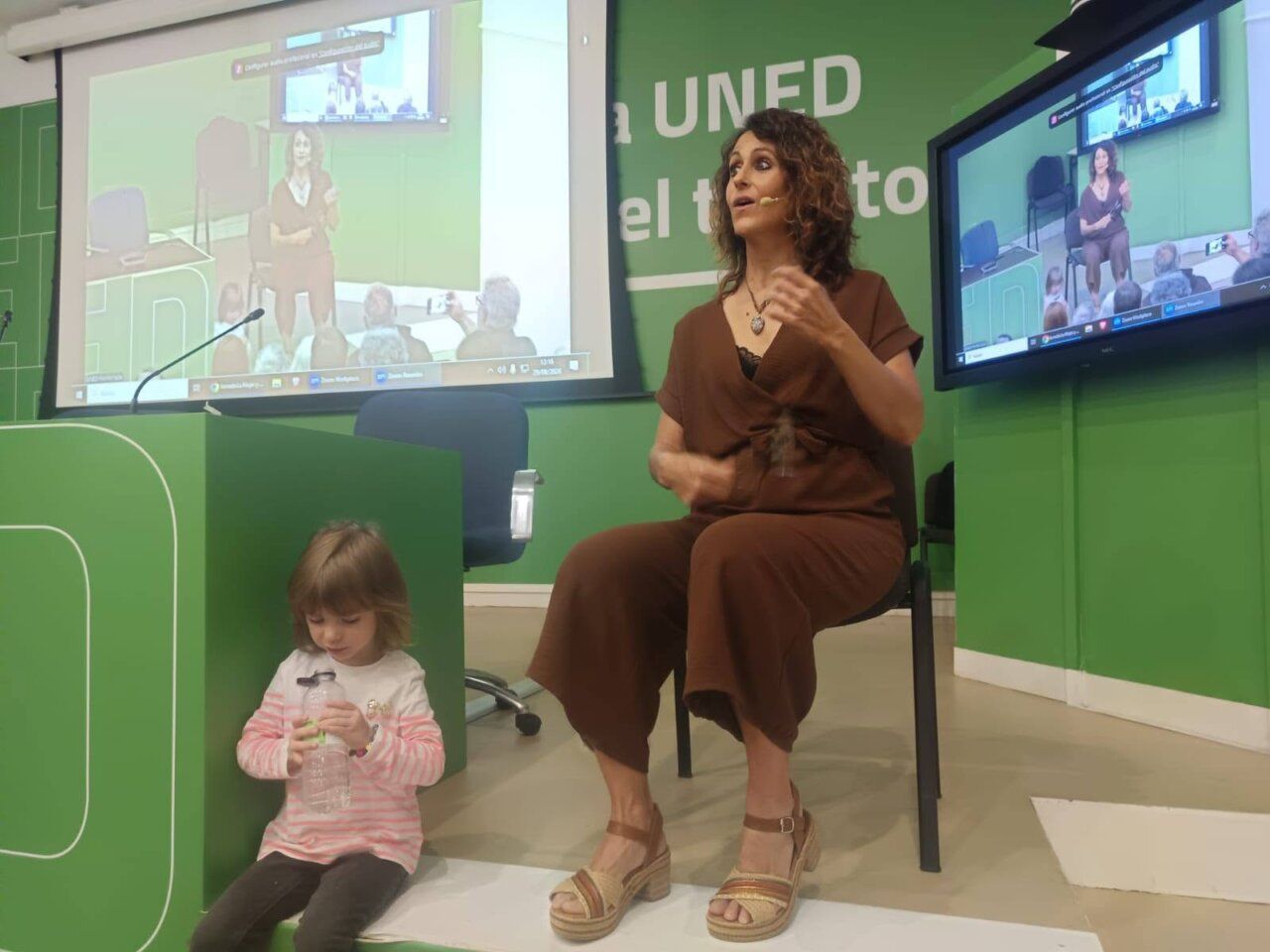 Mujer hablando en un evento sobre música y cultura con una niña a su lado