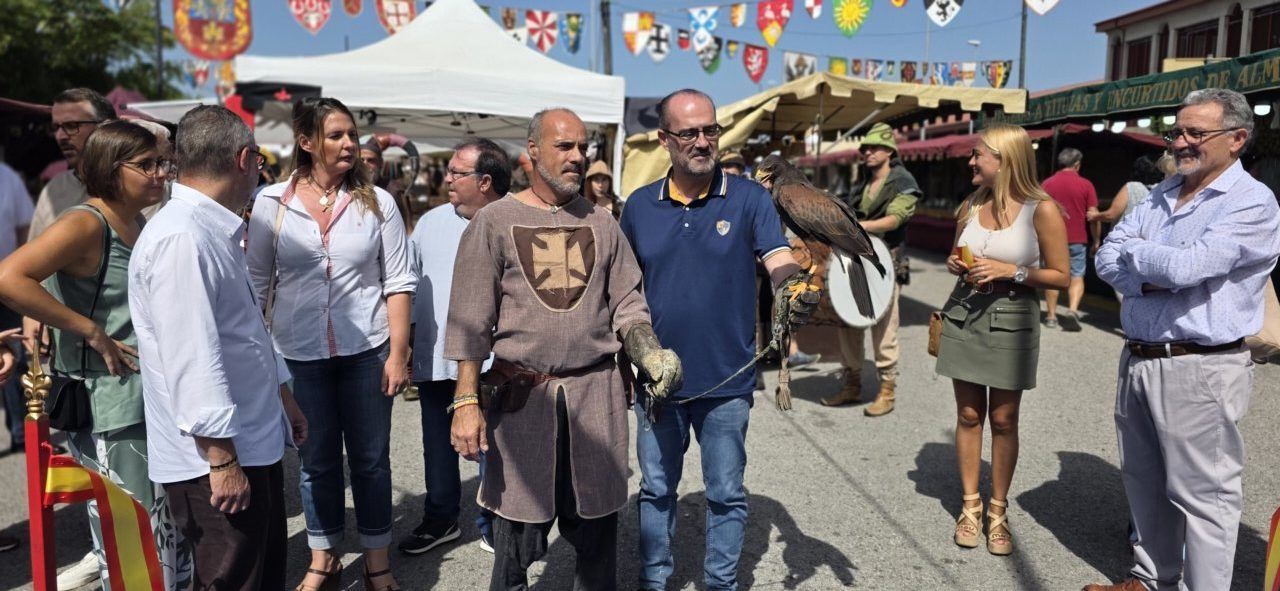 Personas en el Mercado Medieval de Ponferrada con vestimenta tradicional y un ave rapaz.