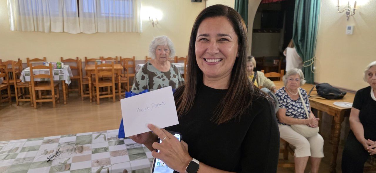 Mujer sonriente sosteniendo un premio en un concurso de postres