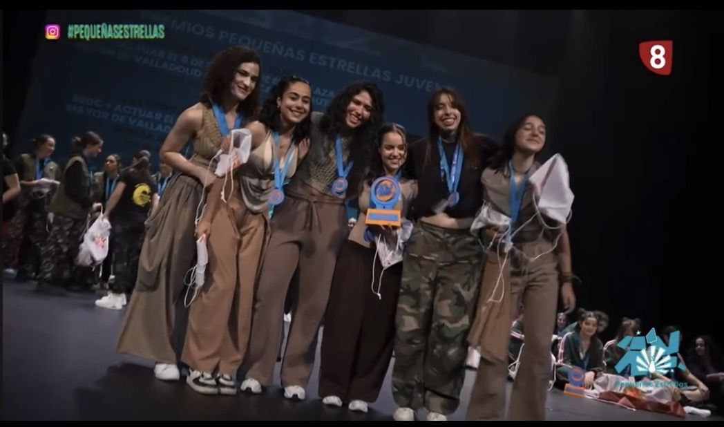 Grupo de jóvenes bailarines con medallas y trofeo en concurso de danza
