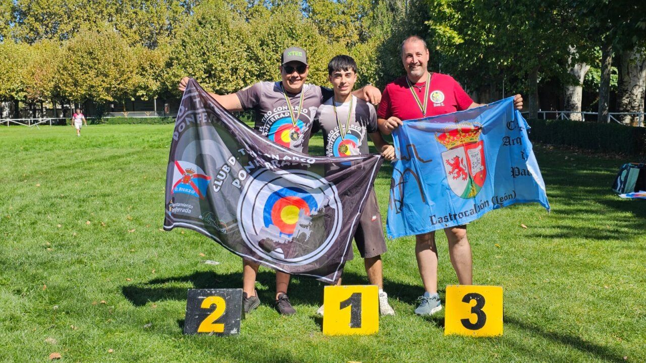 Tres personas sosteniendo banderas en un evento deportivo al aire libre