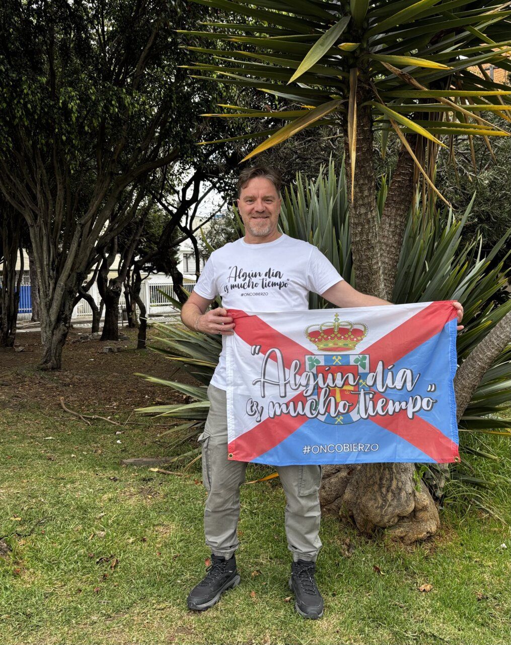 Hombre sosteniendo una bandera de Oncobierzo en un parque