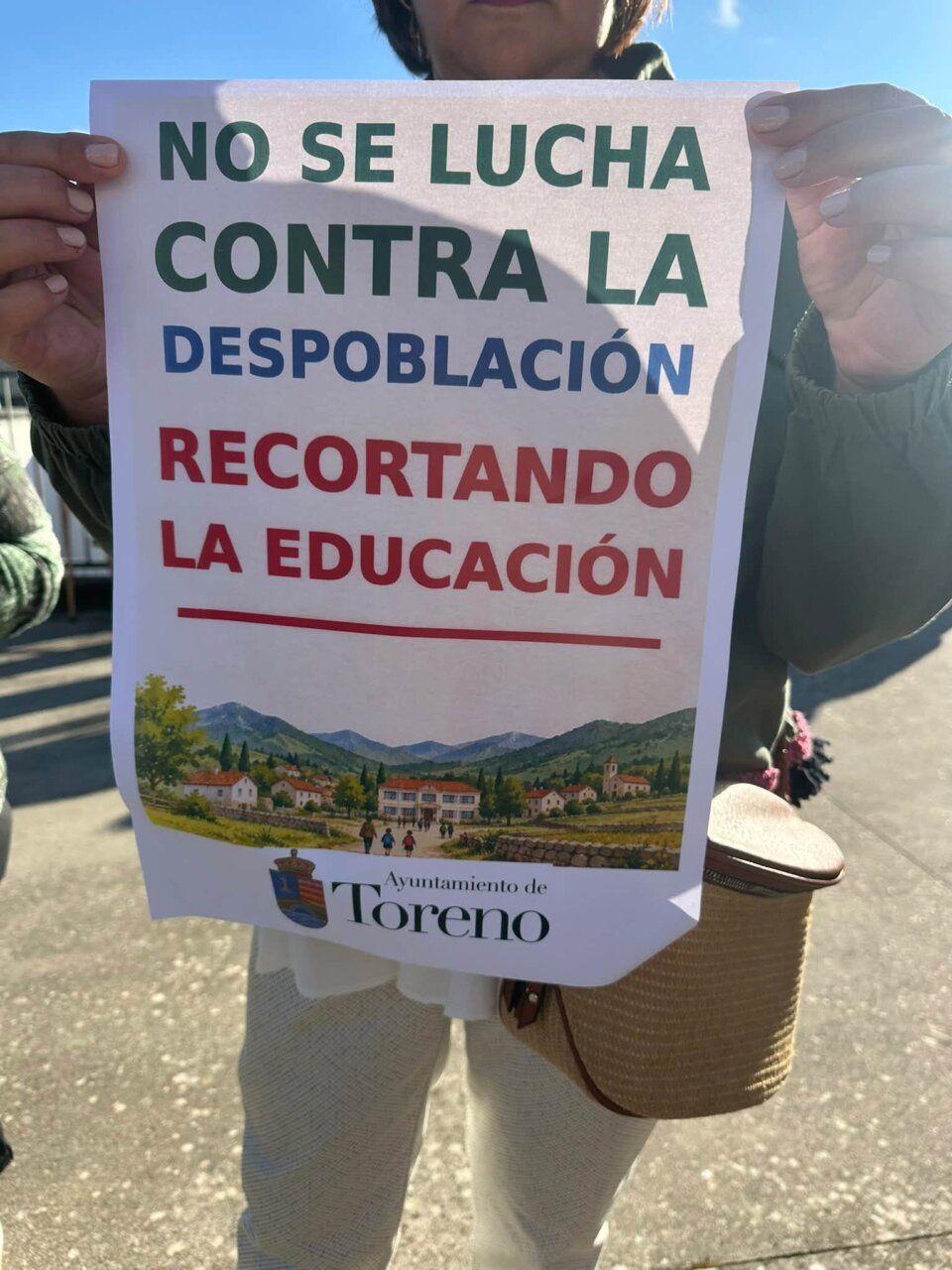Persona sosteniendo un cartel sobre la educación y despoblación en Toreno