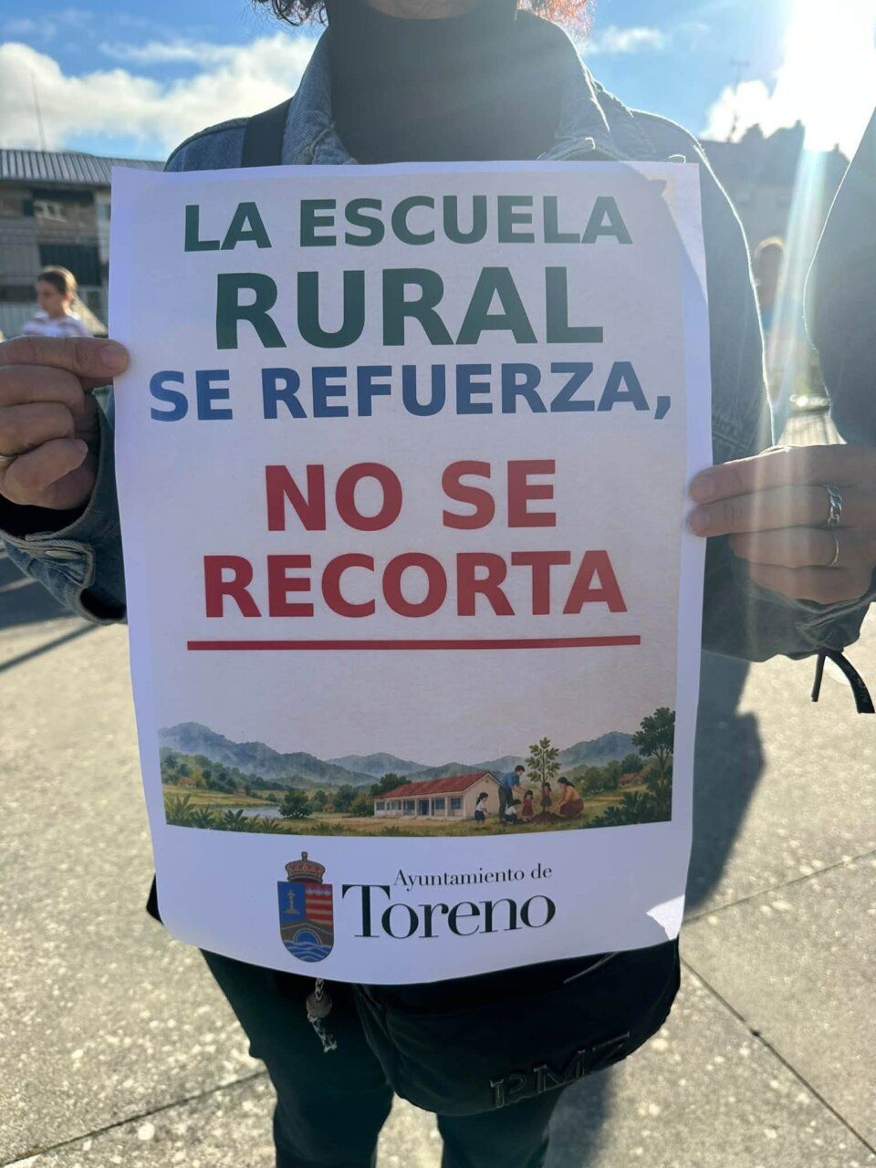 Persona sosteniendo un cartel sobre la educación en Toreno