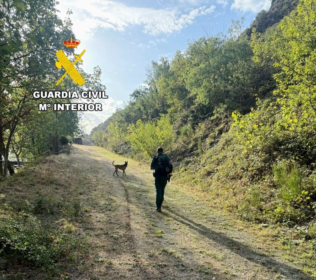 Agente de la Guardia Civil caminando por un sendero con un perro