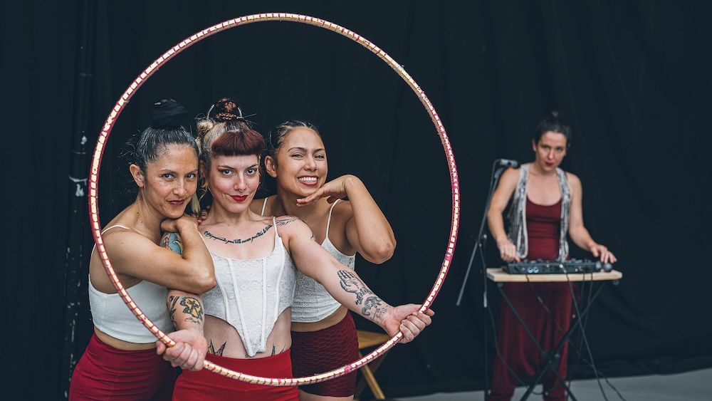 Tres artistas de circo posando con aros en un escenario