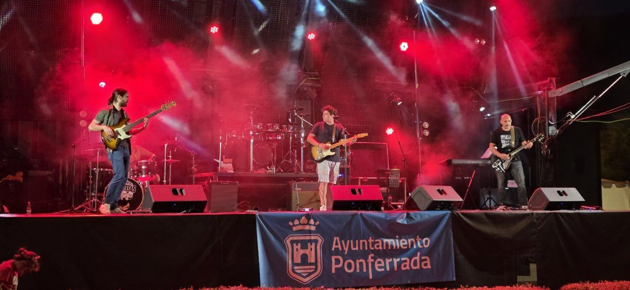 Banda tocando en un escenario con luces rojas en Ponferrada