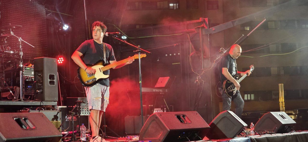 Músicos tocando en un escenario con luces rojas durante un concierto