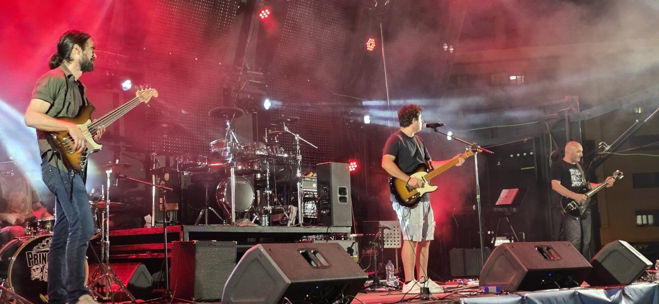 Banda tocando en un concierto con luces y humo en el escenario