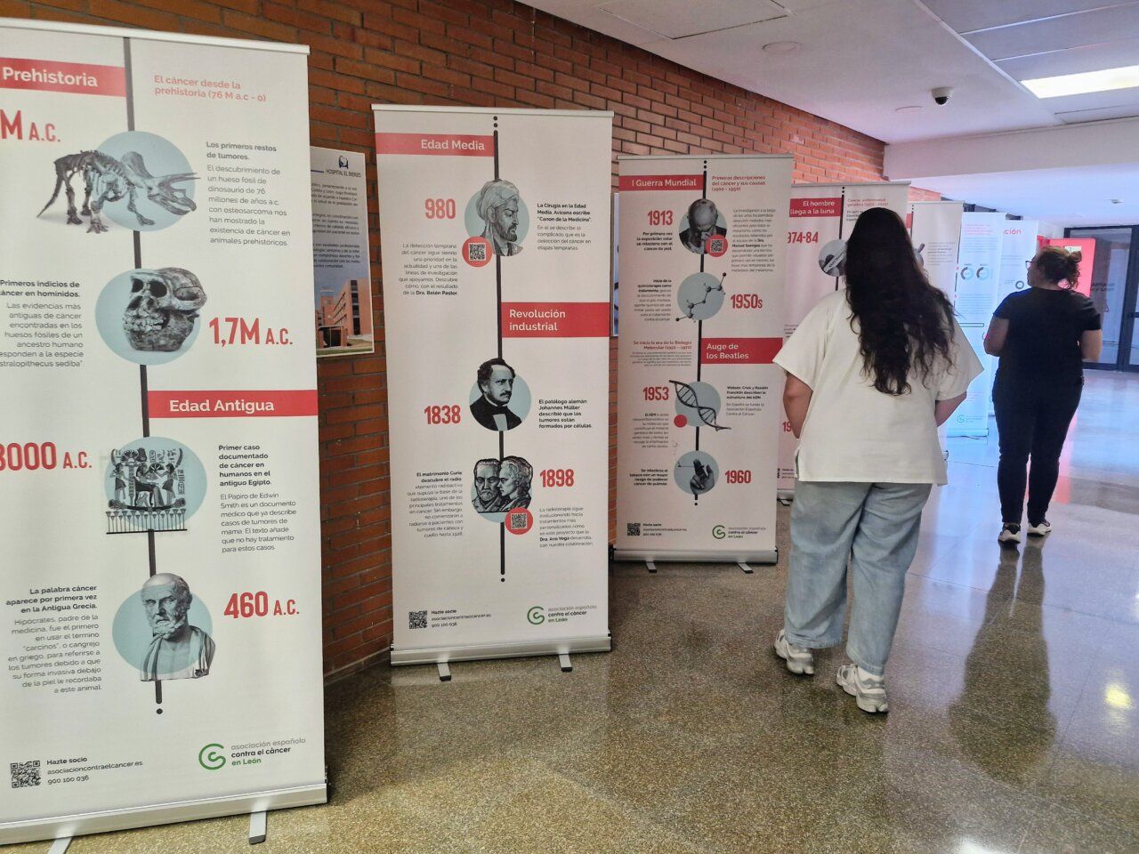 Dos personas observan la exposición sobre investigación del cáncer en el hospital.