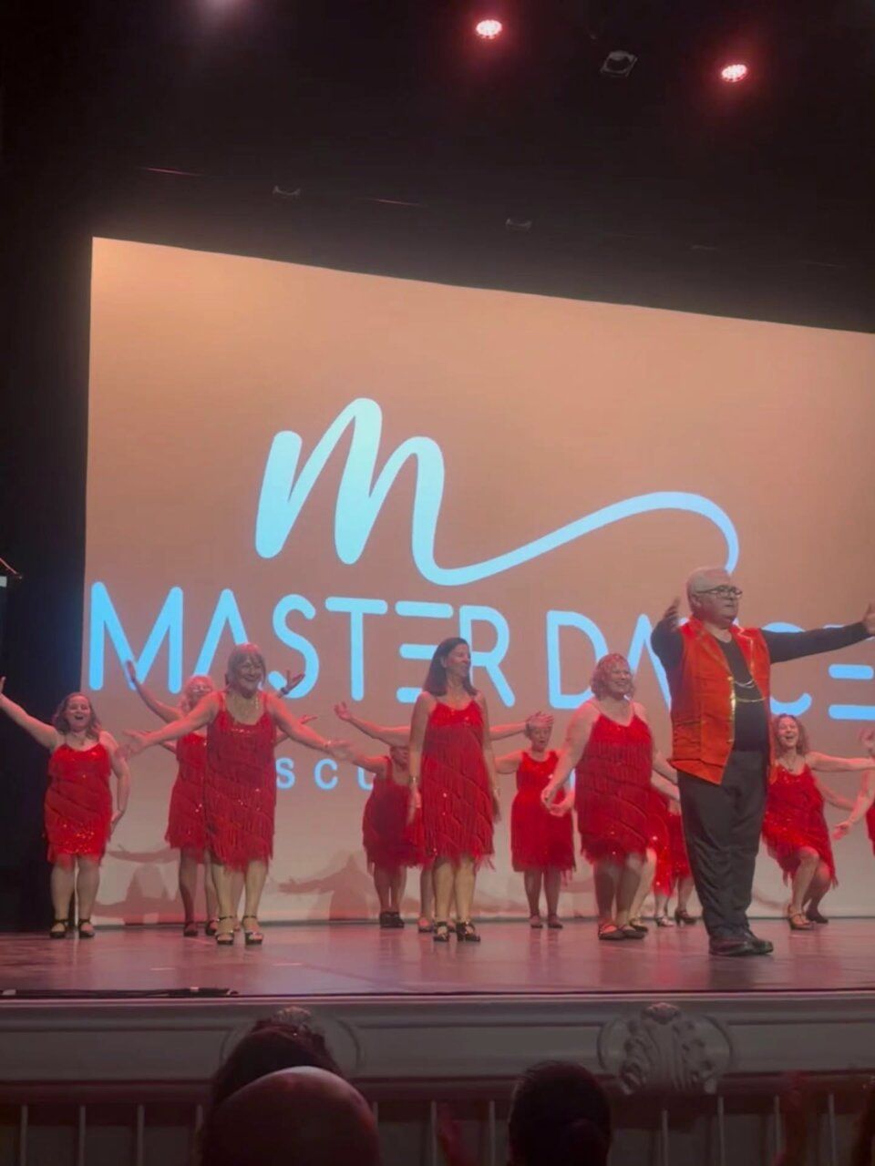 Acto de gala benéfica con participantes en vestuario rojo en escenario
