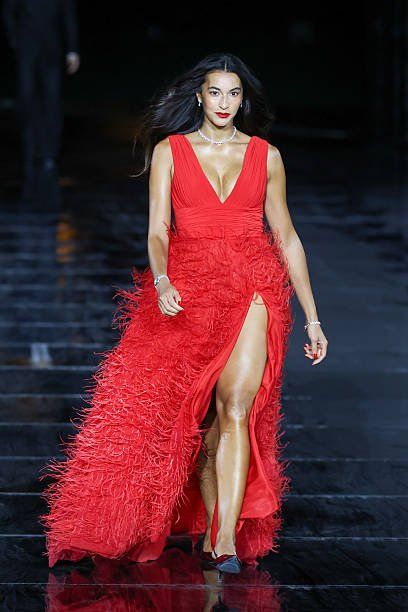 Modelo desfilando con vestido rojo de plumas en pasarela