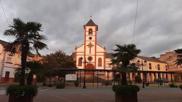 Iglesia en Toral de los Vados con palmeras y cielo nublado