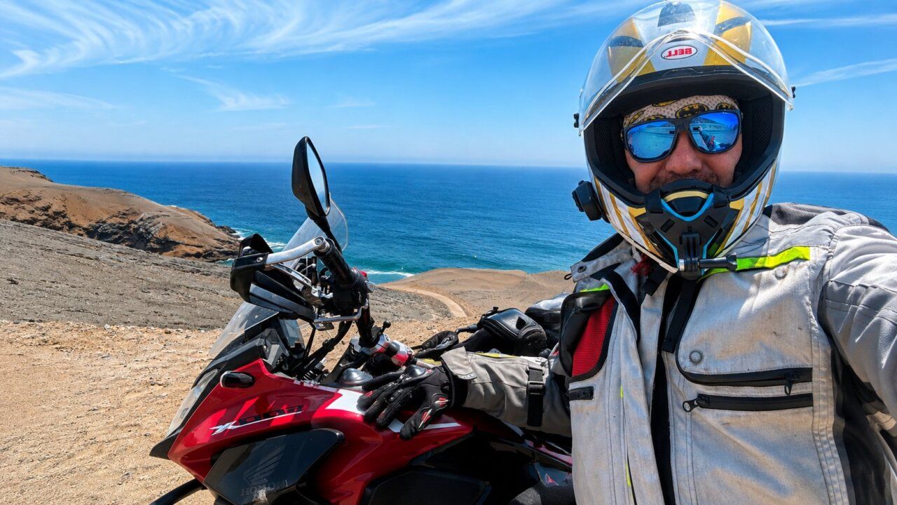Carlos García Ruiz en su moto frente al océano durante su viaje por Sudamérica.