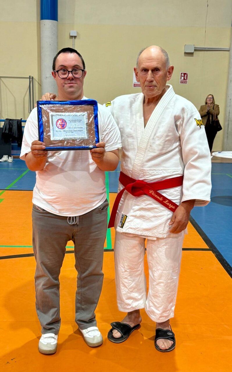 Dos hombres sosteniendo un reconocimiento en un evento de judo.